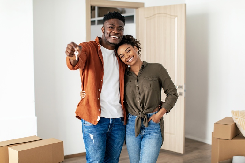 black millenial couple posing in new house with key
