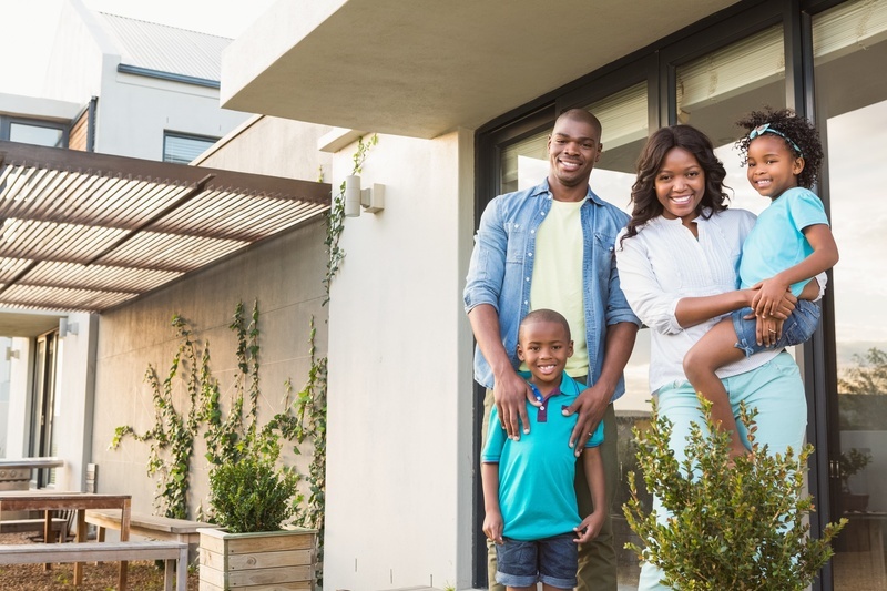black family happily posing in front of their home